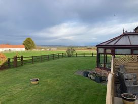 A garden with a conservatory and grass at Bumble Bee Lodge in Muston