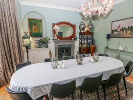 A dining room with a long table and a fireplace at The Old Vicarage in Carmarthen