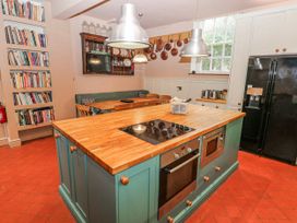 A kitchen with wooden island and shelves of books at The Old Vicarage in Carmarthen