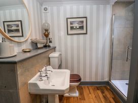A bathroom with a sink, toilet, shower, and mirror at The Old Vicarage in Carmarthen