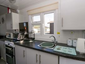 A kitchen with sink, cupboard, microwave and window at The Comfort Den near Aberystwyth