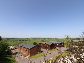 A view of cabins with a grassy area and trees at 33 Pendle View in Clitheroe