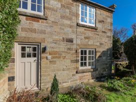 A stone cottage exterior with windows and a door at Holly Cottage in Whitby