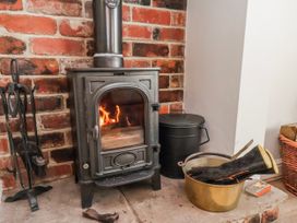 A stove with firewood and tools in a living room at Holly Cottage in Whitby