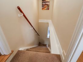 A staircase with a handrail and a picture on the wall at Holly Cottage in Whitby