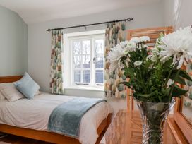 A bedroom with a bed and flowers on the nightstand at Holly Cottage in Whitby