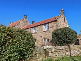 A house with stone walls and a bush at Holly Cottage in Whitby