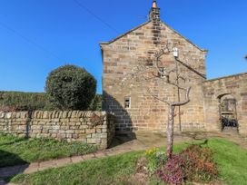A garden with a stone wall and tree at Holly Cottage in Whitby