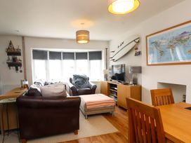 A living room with a sofa, television, and dining table at 7 Sisial Y Mor, Rhosneigr