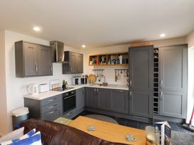 A kitchen with grey cabinets and appliances at 7 Sisial Y Mor in Rhosneigr