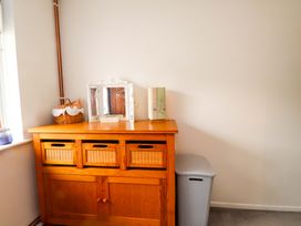 A wooden cabinet with baskets and decorative items at 7 Sisial Y Mor in Rhosneigr