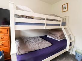 A bedroom with a bunk bed and a television at 7 Sisial Y Mor in Rhosneigr