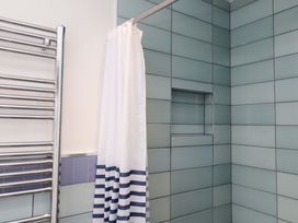 A bathroom with a shower curtain and towel rail at 7 Sisial Y Mor in Rhosneigr