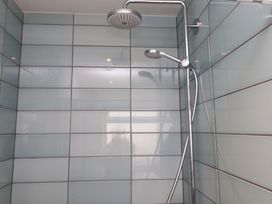 A shower area with a showerhead and tiled walls at 7 Sisial Y Mor Rhosneigr