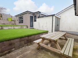 A garden with artificial grass and a wooden table at 7 Sisial Y Mor Rhosneigr