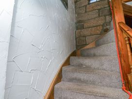 A staircase with carpet and a stone wall at Bishop's Cottage in Whitby
