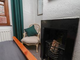 A bedroom featuring a chair, fireplace, and curtain at Bishop's Cottage in Whitby