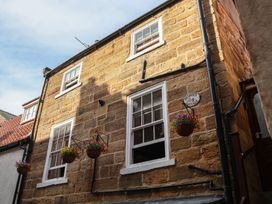 A stone building with windows and flower pots at Bishop's Cottage in Whitby