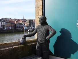 A statue holding a lantern near the water at Bishop's Cottage in Whitby