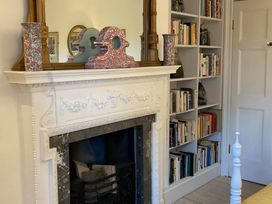 A living room with a fireplace and bookshelf at Groves Hall Garden Apartment Whitby