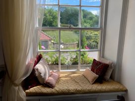 A window seat with cushions and a view of flowers at Groves Hall Garden Apartment Whitby