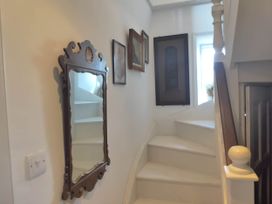 A staircase with a mirror and framed pictures at Groves Hall Garden Apartment Whitby