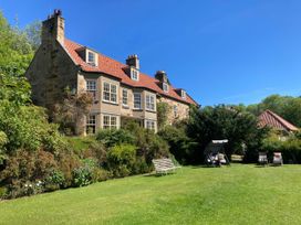 A garden with a building and seating at Groves Hall Garden Apartment Whitby