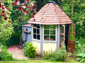A garden shed with a conical roof and open door in a garden at Groves Hall Garden Apartment Whitby