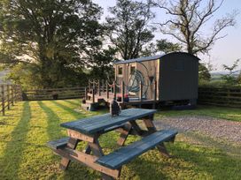 An outdoor area with a shepherd's hut and a bench at The Peacock Shepherds Hut at Hafoty Boeth, Corwen