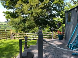 A deck area with a flower pot and fence at The Peacock Shepherds Hut at Hafoty Boeth Corwen