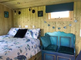 A bedroom with a bed and bench seating at The Peacock Shepherds Hut at Hafoty Boeth, Corwen