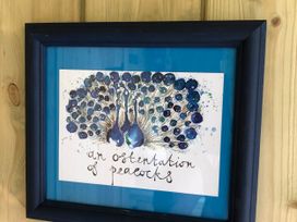 Framed artwork of peacocks on a blue background at The Peacock Shepherds Hut at Hafoty Boeth in Corwen