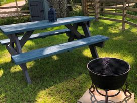 A picnic table and grill in a garden at The Peacock Shepherds Hut at Hafoty Boeth, Corwen