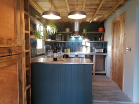 A kitchen with an island and wooden shelves at Stone Moor Lodge, Justin's Peak District Base Camp, Sheffield