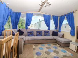 A living room with a sectional sofa and dining table at PK Sunset View in Corton