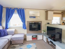 A living room with a sofa and televisions at PK Sunset View in Corton