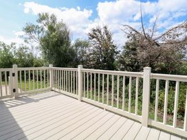A deck area with railing and trees in the background at PK Sunset View in Corton