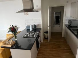 A kitchen with a stove, sink, and flower vase at Seaside Cottage Escape in Paignton