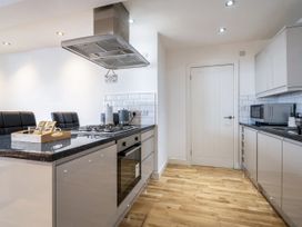 A kitchen with a stove, oven, and bar stools at Seaside Cottage Escape in Paignton