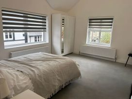 A bedroom featuring a bed, wardrobe, radiator, and windows at Llangollen - House - Sleeps 8- Garden in Llangollen