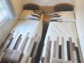 A bedroom with two single beds and a window at Llanarmon-yn-Ial Mold 3-Bed Caravan, Sleeps 6 Llanarmon-Yn-Ial