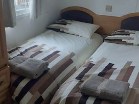 A bedroom with two beds and towels at Llanarmon-yn-Ial Mold 3-Bed Caravan, Sleeps 6 in Llanarmon-Yn-Ial