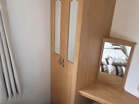 A wardrobe with a mirror and table in a bedroom at Llanarmon-yn-Ial Mold 3-Bed Caravan, Sleeps 6 Llanarmon-Yn-Ial