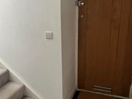 A hallway with stairs and a closed wooden door at Modern Seaside Cottage - Sleeps 5, Paignton