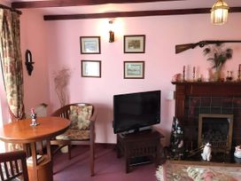 A living room with a table and television at Converted Stone Barn -20 Acres - Farm Animals! in Corwen