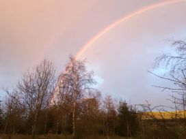 A rainbow in the sky above trees at Converted Stone Barn -20 Acres - Farm Animals! Corwen