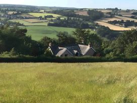 A house in a field surrounded by trees and hills at Converted Stone Barn -20 Acres - Farm Animals! Corwen