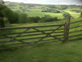 A view of a field with a wooden gate at Converted Stone Barn -20 Acres - Farm Animals in Corwen