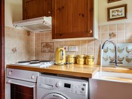 A kitchen with a stove, washing machine, and sink at Converted Stone Barn -20 Acres - Farm Animals! Corwen