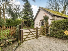 A house with a gravel driveway and wooden gate at Converted Stone Barn -20 Acres - Farm Animals! in Corwen